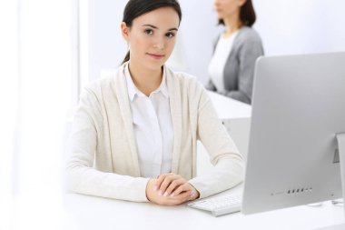 Ofiste bilgisayarla çalışan bir iş kadını, arka planda çalışan bir iş arkadaşı. Masada otururken avukatın ya da muhasebecinin vesikalığı.