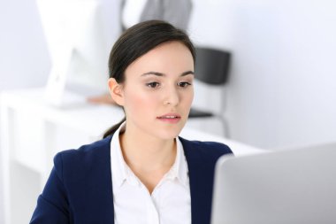 Ofiste bilgisayarla çalışan bir iş kadını, arka planda çalışan bir iş arkadaşı. Masada otururken avukatın ya da muhasebecinin vesikalığı.