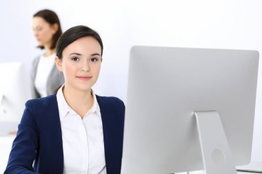 Ofiste bilgisayarla çalışan bir iş kadını, arka planda çalışan bir iş arkadaşı. Masada otururken avukatın ya da muhasebecinin vesikalığı.