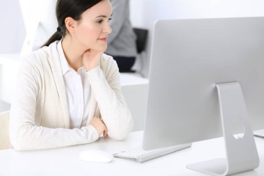 Ofiste bilgisayarla çalışan bir iş kadını, arka planda çalışan bir iş arkadaşı. Masada otururken avukatın ya da muhasebecinin vesikalığı.