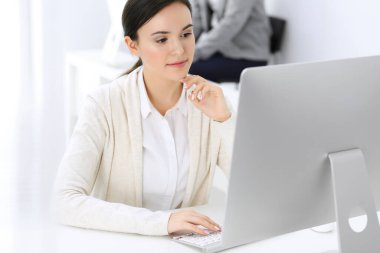 Ofiste bilgisayarla çalışan bir iş kadını, arka planda çalışan bir iş arkadaşı. Masada otururken avukatın ya da muhasebecinin vesikalığı.