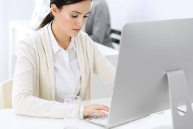 Ofiste bilgisayarla çalışan bir iş kadını, arka planda çalışan bir iş arkadaşı. Masada otururken avukatın ya da muhasebecinin vesikalığı.