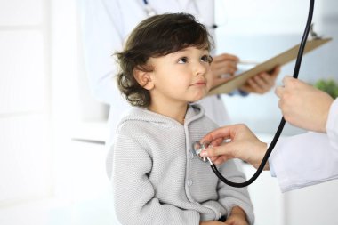 Doktor steteskopla çocuk bir hastayı muayene ediyor. Doktor randevusunda tatlı bir Arap çocuk. Tıp ve sağlık hizmetleri kavramı