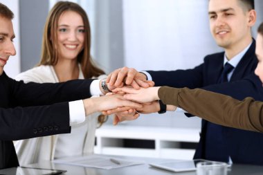 Takım çalışması yapan ve el ele tutuşan iş adamları grubu ya da modern ofiste kontrat imzaladıktan sonra beş kişi. Meslektaşları ya da avukatları olan tanınmamış işadamı ve kadın elleriyle daire çiziyor.