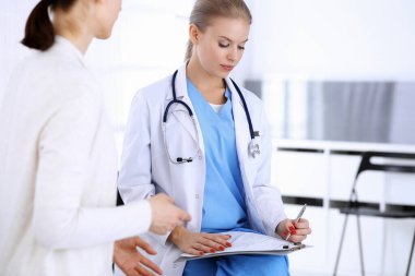 Muayene sırasında doktor ve hasta. Acil serviste portre çekimi yaparken ilaç geçmişini dolduran bir doktor. İlaç ve sağlık hizmetleri kavramı