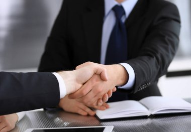 İş adamı, modern ofiste iş arkadaşı veya ortağıyla el sıkışıyor. Yakın plan. Toplantıda bilinmeyen iş adamları var. Takım çalışması, ortaklık ve el sıkışma kavramı