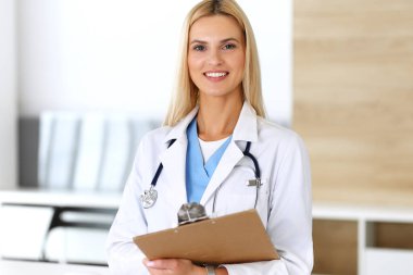 Hastanedeki doktor kadın mesleğinden dolayı heyecanlı ve mutlu. Sarışın doktor ilaç kayıtlarını ve sınav sonuçlarını pano kullanarak kontrol ediyor. Tıp ve sağlık hizmetleri kavramı