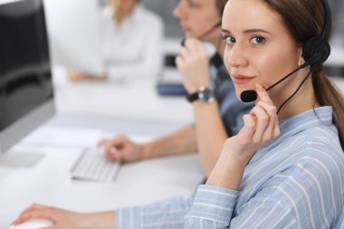 Merkezi ara. İş yerinde sıradan giyinmiş bir grup operatör. Müşteri hizmetleri ofisinde kulaklık takan iş kadınına odaklan. İş dünyasındaki haberleşmeler