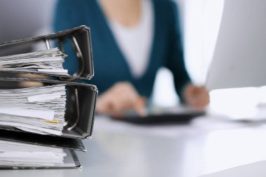 Belgeleri olan pankartlar iş kadını ya da ofisteki büroda çalışan muhasebeci tarafından işleme konmayı bekliyor. İç Vergi ve Denetim kavramı