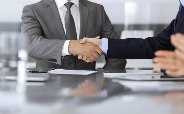 Pessoas de negócios desconhecidas estão apertando as mãos após a assinatura do contrato no escritório moderno, close-up. aperto de mão como final de negociação bem sucedido — Fotografia de Stock