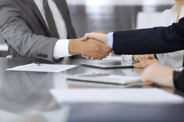 Handshake as successful negotiation ending, close-up. Unknown business people shaking hands after contract signing in modern office