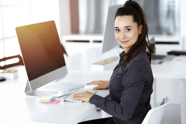 Business woman using computer at workplace in sunny office. Working for pleasure and success