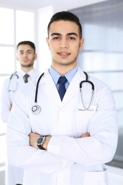 Médico árabe de pie con colega caucásico en consultorio médico o clínica. Equipo de médicos diversos, medicina y concepto de salud — Foto de Stock