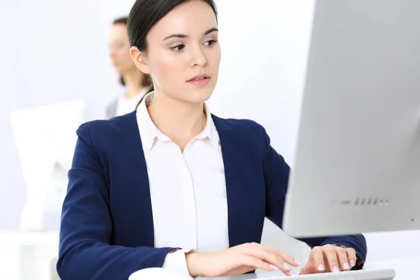 Mujer de negocios que trabaja con la computadora en la oficina, colega de fondo. Imagen de Abogado o Contador en el trabajo mientras está sentado en el escritorio —  Fotos de Stock