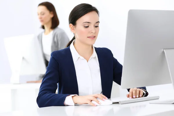 Mujer de negocios que trabaja con la computadora en la oficina, colega de fondo. Imagen de Abogado o Contador en el trabajo mientras está sentado en el escritorio —  Fotos de Stock