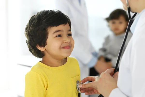 Arzt untersucht eine Kinderpatientin mit einem Stethoskop. Netter arabischer Junge beim Arzttermin. Medizin und Gesundheitskonzept — Stockfoto