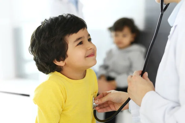 Medico che esamina un paziente infantile mediante stetoscopio. Carino il ragazzo arabo all'appuntamento dal medico. Medicina e concetto di assistenza sanitaria — Foto Stock