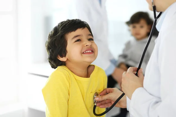 Médico examinando a un niño paciente por estetoscopio. Lindo chico árabe en la cita con el médico. Concepto de medicina y salud — Foto de Stock