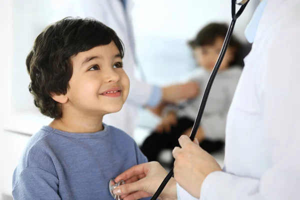 Médico examinando uma criança paciente por estetoscópio. Rapaz árabe bonito na consulta médica. Conceito de medicina e saúde — Fotografia de Stock