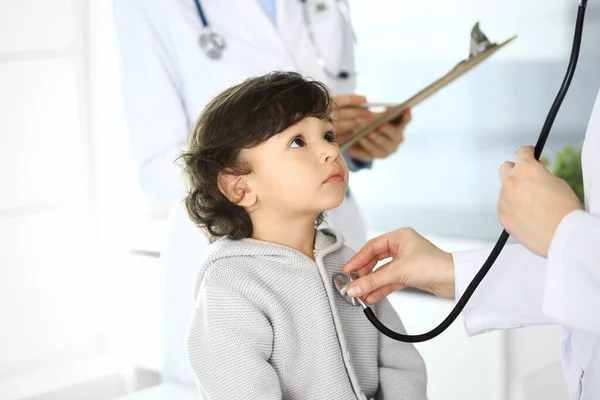 Médico examinando a un niño paciente por estetoscopio. Lindo chico árabe en la cita con el médico. Concepto de medicina y salud —  Fotos de Stock