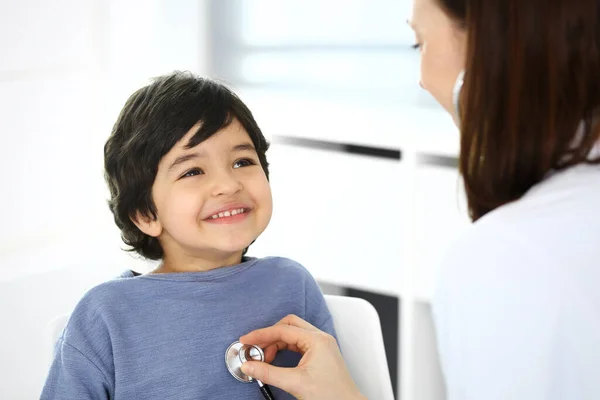 Arzt untersucht eine Kinderpatientin mit einem Stethoskop. Netter arabischer Junge beim Arzttermin. Medizin und Gesundheitskonzept — Stockfoto