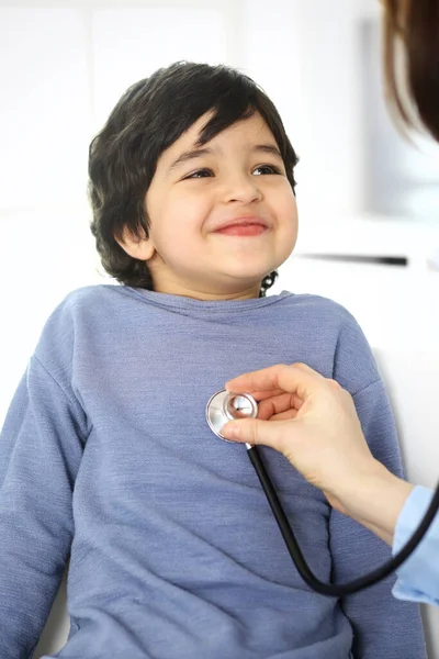 Médico examinando uma criança paciente por estetoscópio. Rapaz árabe bonito na consulta médica. Conceito de medicina e saúde — Fotografia de Stock