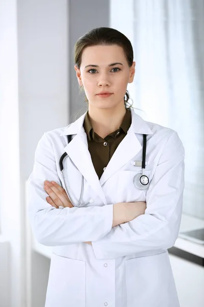 Doctora mujer feliz y alegre mientras está de pie en la oficina del hospital. Servicio médico perfecto en la clínica. Concepto de medicina y salud — Foto de Stock