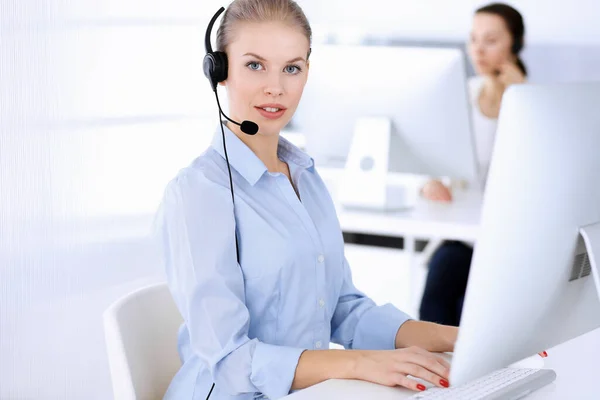 Ligue para o escritório. Mulher loira bonita usando computador e fone de ouvido para consultar clientes on-line. Grupo de operadores que trabalham como ocupação de serviço ao cliente. Conceito de empresários — Fotografia de Stock