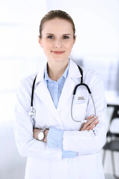 Dottoressa donna colpita alla testa al lavoro in ospedale. Medico in piedi dritto e sorridente, ritratto in studio. Medicina e concetto di assistenza sanitaria — Foto Stock