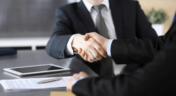 Empresário apertando as mãos com seu colega ou parceiro acima da mesa de vidro no escritório moderno, close-up. Pessoas de negócios desconhecidas na reunião. Trabalho em equipe, parceria e conceito de aperto de mão — Fotografia de Stock