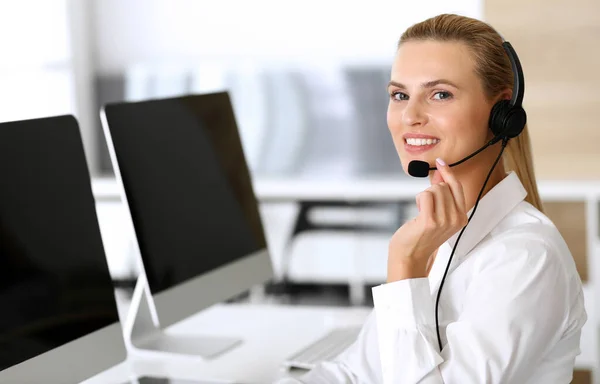 Volejte centrálu. Šťastné a vzrušené obchodní žena pomocí sluchátka při konzultaci klientů on-line. Oddělení zákaznického servisu nebo telemarketingu. Usmívající se blondýnka v práci — Stock fotografie