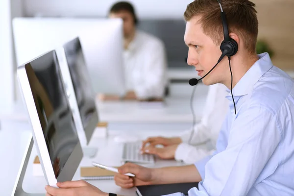 Centro de llamadas. Grupo de operadores diversos en el trabajo. Enfócate en hombre de negocios con auriculares en la oficina de servicio al cliente. Concepto empresarial —  Fotos de Stock