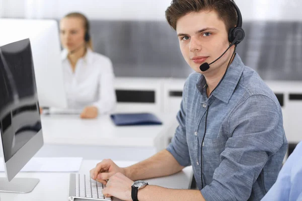 Call center. Group of casual dressed operators at work. Focus on young businessman in headset at customer service office. Telesales in business — Stock Photo, Image