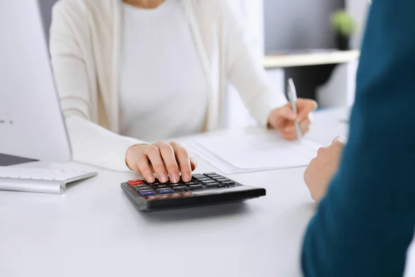 Contador que comprueba el estado financiero o cuenta por la renta de la calculadora para el formulario de impuestos, manos de cerca. Mujer de negocios sentada y trabajando con su colega en el escritorio en la oficina tonificado en azul. Impuestos y —  Fotos de Stock