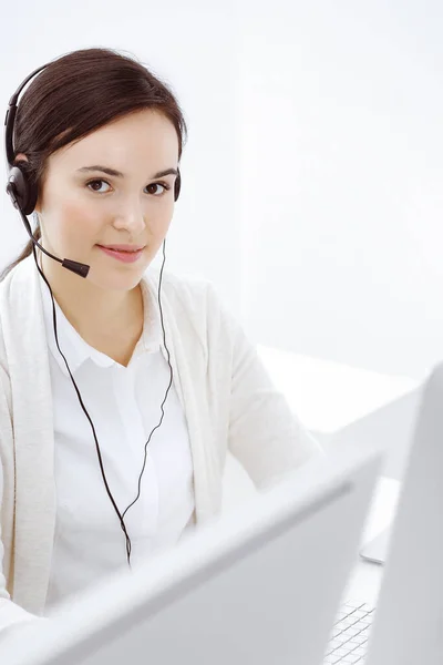 Centro de llamadas. Mujer vestida casual sentada y trabajando en auriculares en la oficina de servicio al cliente. Concepto empresarial —  Fotos de Stock