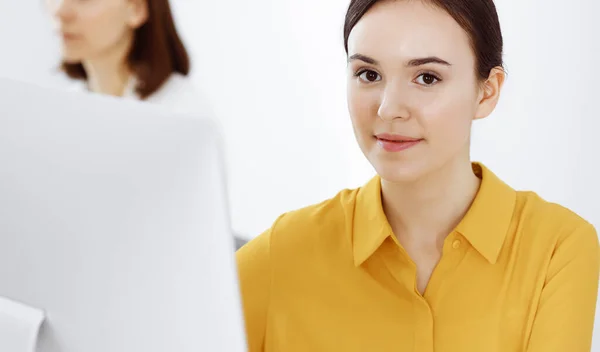 Affärskvinna i senapsfärgad blus tittar på kameran på kontoret, headshot — Stockfoto