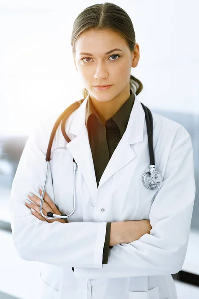 Γυναίκα-γιατρός στέκεται και κοιτάζει την κάμερα στην ηλιόλουστη κλινική. Τέλεια ιατρική υπηρεσία. Ιατρική και υγειονομική περίθαλψη — Φωτογραφία Αρχείου