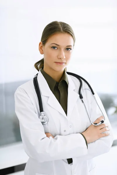 女医生交叉着胳膊站在那里，看着镜头。完美的医疗服务在诊所。医药和保健 — 图库照片