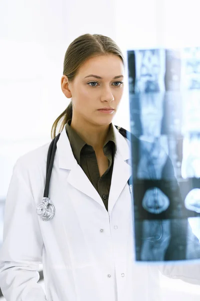 Woman-doctor examining x-ray picture in hospital. Surgeon or orthopedist at work in clinic. Medicine and healthcare concept — Stock Photo, Image