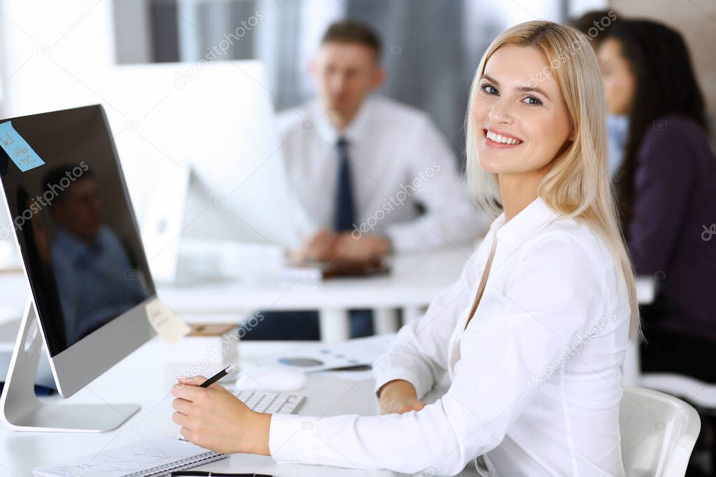 Business woman using computer at workplace in modern office. Secretary or female lawyer smiling and looks happy. Working for pleasure and success