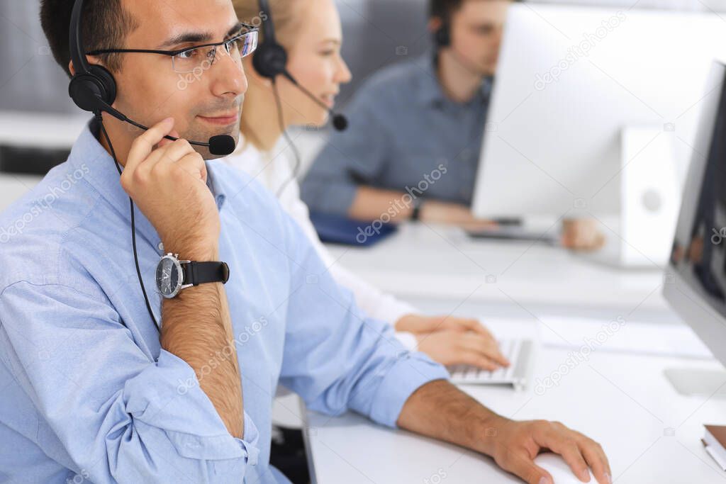 Call center. Group of casual dressed operators at work. Focus on adult businessman in headset at customer service office. Telesales in business