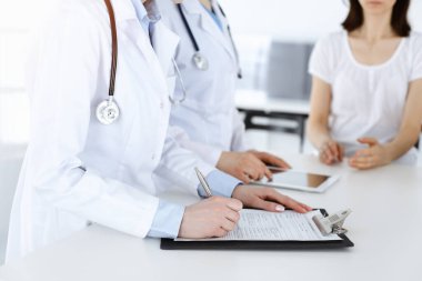İş yerindeki bilinmeyen kadın doktorlar hastalara danışıyor. Tıbbi belgeleri ya da reçeteleri dolduran kadın doktorlar, yakın çekim