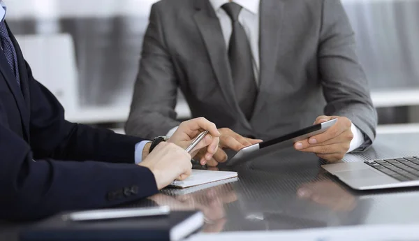 Hombre de negocios desconocido que utiliza la computadora de la tableta y el trabajo junto con su colega mientras se sienta en el escritorio de cristal en la oficina moderna. Trabajo en equipo y concepto de asociación — Foto de Stock