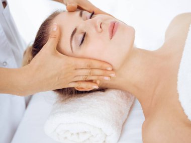 Genç ve sarışın kadın spa salonunda yüz masajından zevk alıyor. Güzellik konsepti