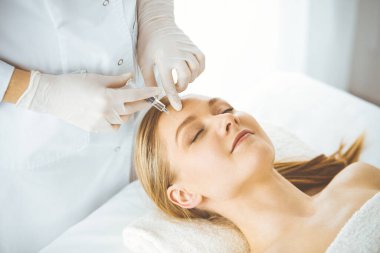 Güzellik doktoru sarışın kadın yüzüne şırıngayla güzellik prosedürü uyguluyor. Kozmetik tıp, güzellik enjeksiyonu konsepti