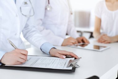 İş yerindeki bilinmeyen kadın doktorlar hastalara danışıyor. Tıbbi belgeleri ya da reçeteleri dolduran kadın doktorlar, yakın çekim