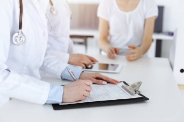 İş yerindeki bilinmeyen kadın doktorlar hastalara danışıyor. Tıbbi belgeleri ya da reçeteleri dolduran kadın doktorlar, yakın çekim