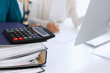 Hesap makinesi ve kağıtlar iş kadını ya da ofisteki büroda çalışan muhasebeci tarafından incelenmeyi bekliyor. İç Vergi ve Denetim kavramı