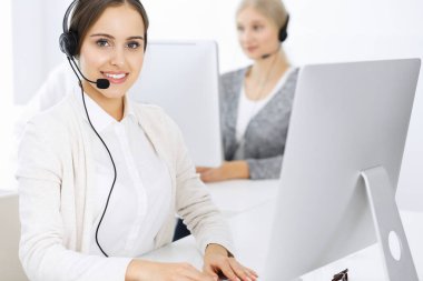 Merkezi ara. Çeşitli operatörler iş başında. Telepazarlama servisinin müşterileriyle iletişim kuran kulaklıklı güzel bir kadın. İş konsepti