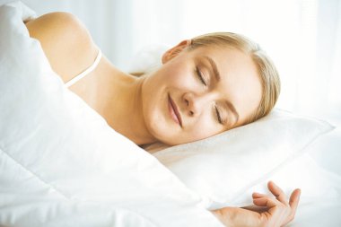 Güzel genç bir kadın yatak odasında rahat ve mutlu bir şekilde uyuyor. Mutlu bir sabah uyanıyorum.